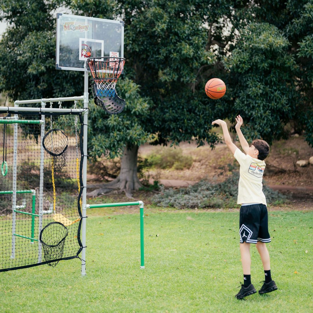Child shooting basketball at hoop mounted on a Funky Monkey Bars frame