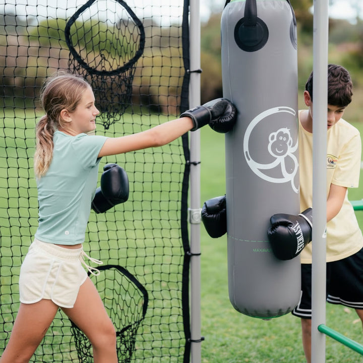 Children using grey outdoor boxing bag on a Funky Monkey Bars backyard frame