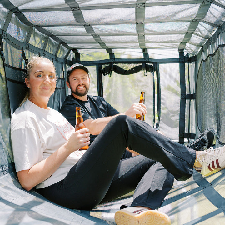 Adults sitting inside black Cubby Clubhouse on Funky Monkey Bars frame