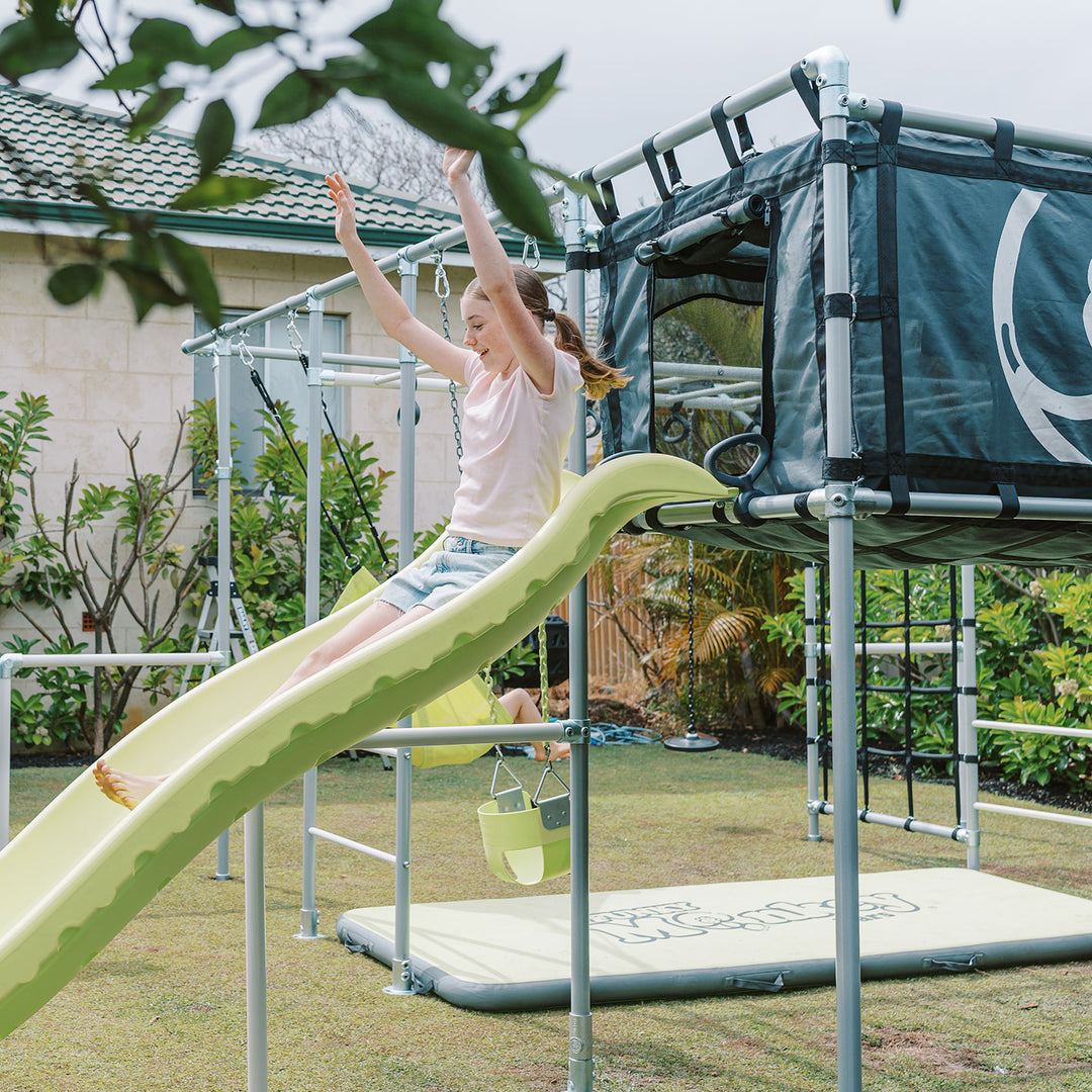 Child climbing on Cubby Clubhouse slide attached to Funky Monkey Bars frame