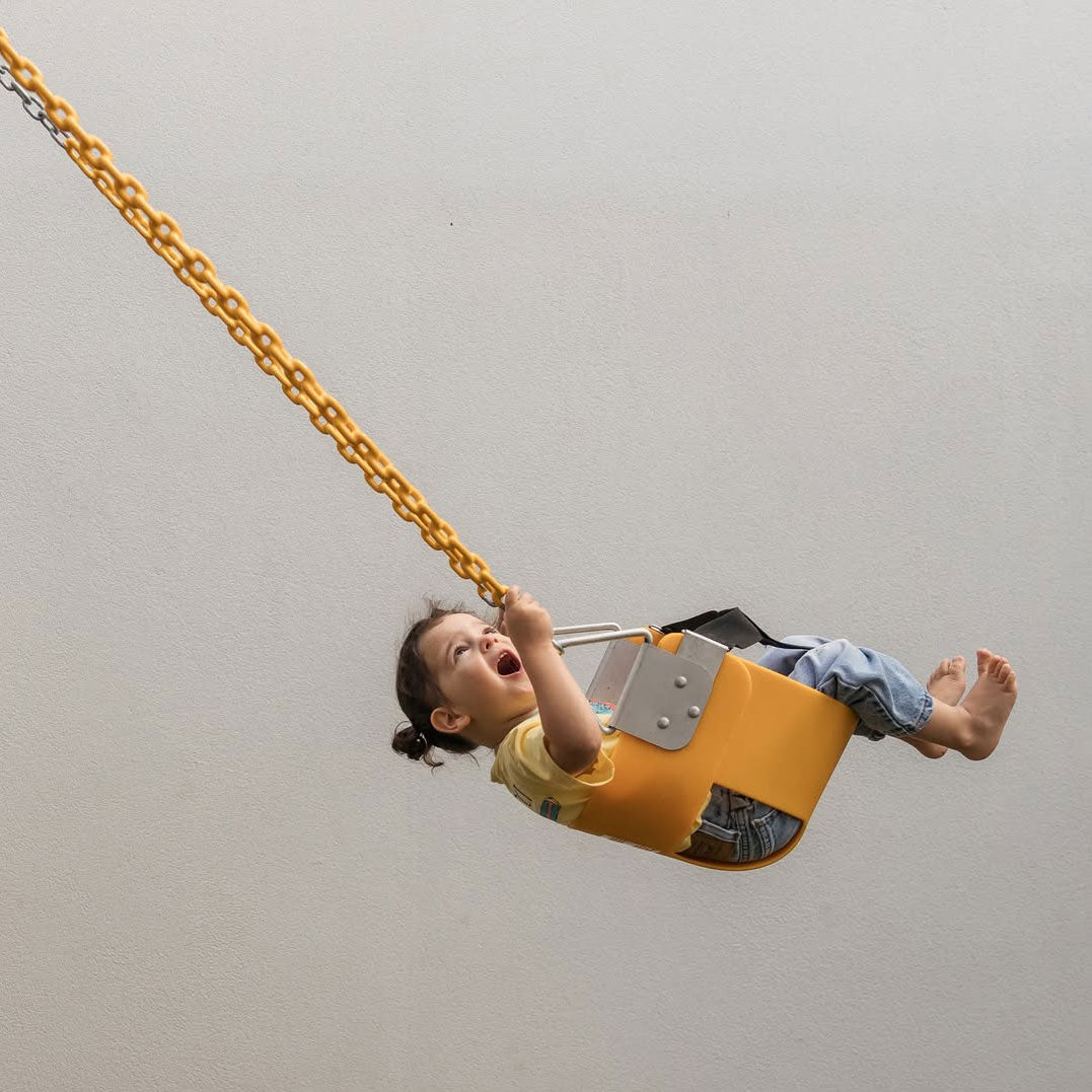 Child riding yellow Funky Monkey Bars Toddler Swing with metal chains and safety strap
