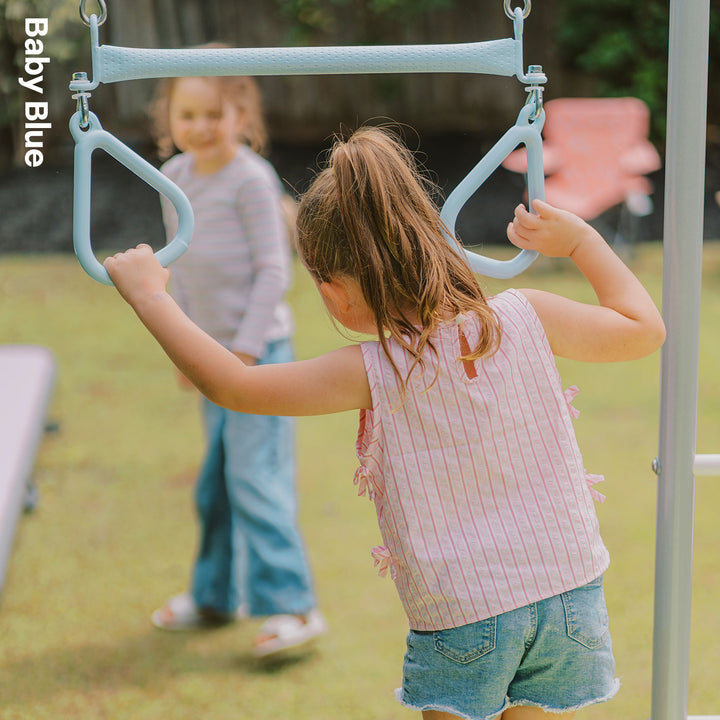Child holding baby blue Funky Monkey Bars Trapeze rings on a backyard monkey bar frame
