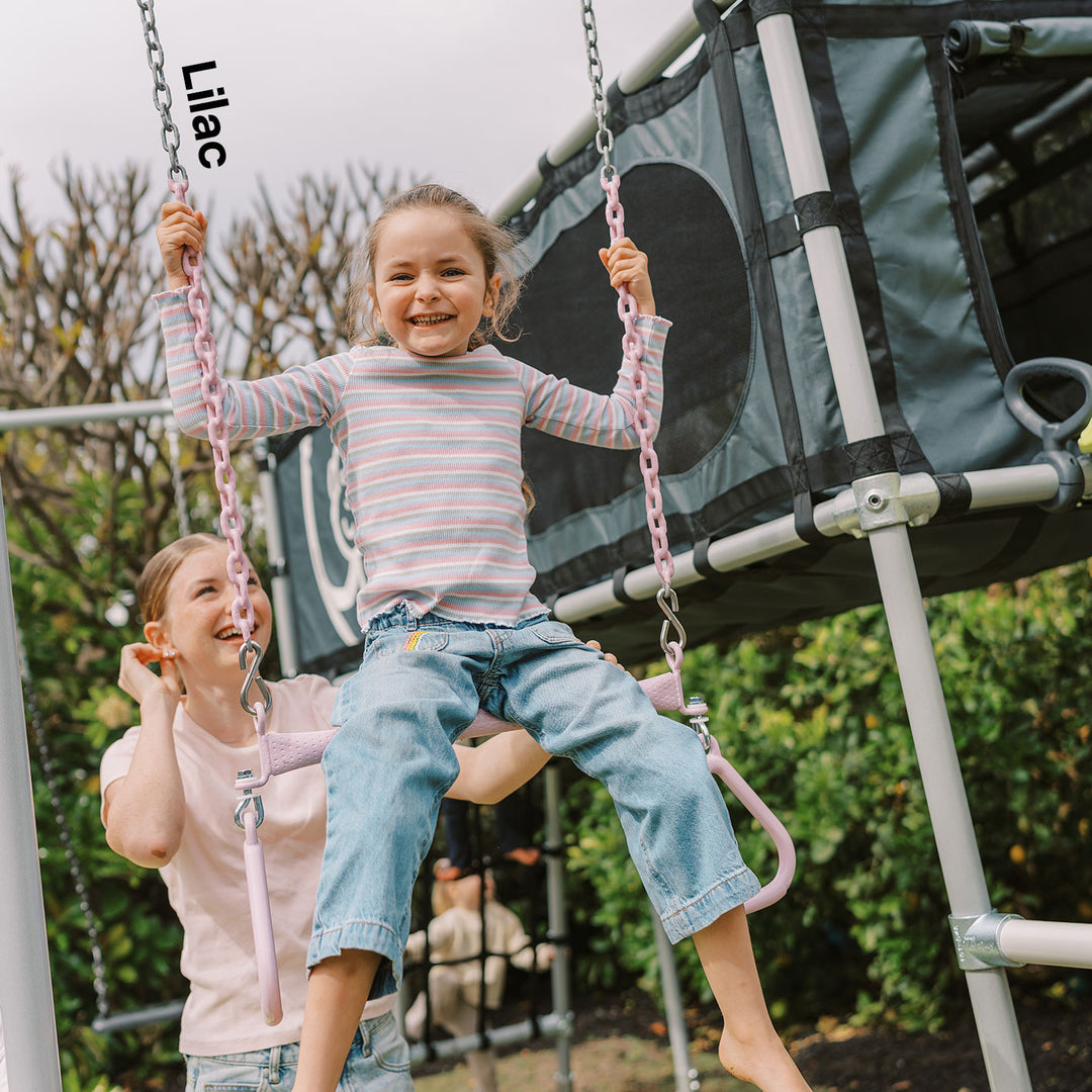 Child using lilac Funky Monkey Bars Trapeze with metal chains on a backyard monkey bar frame