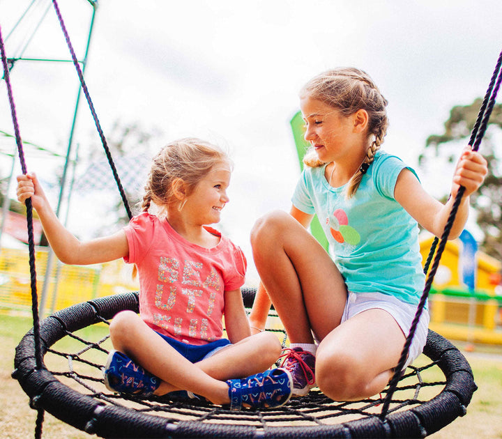 kids sitting on nest swing